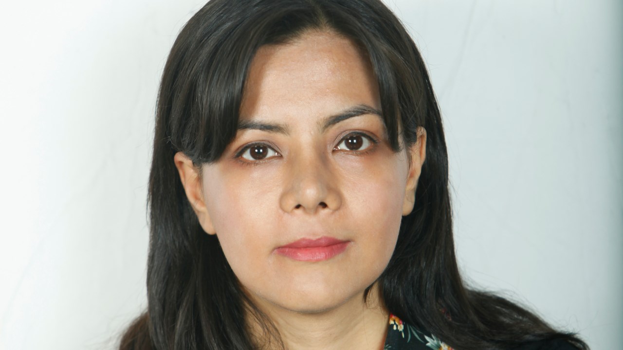 Porträttbild av  kvinna i mörkt hår, med vit bakgrund 