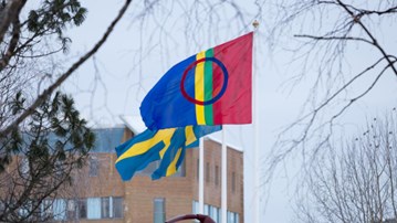 Den samiska flaggan vajar bredvid två svenska på flaggstängerna på campus Umeå.