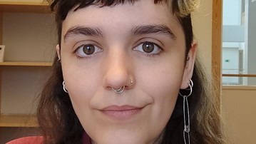 Kvinna med mörkt långt hår, kort lugg och röd skjorta.