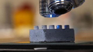 En legobit i cement under ett mikroskop