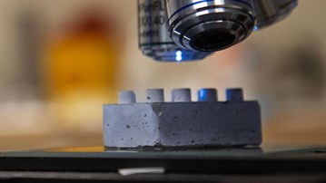 En legobit i cement under ett mikroskop