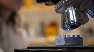 En legobit i cement under ett mikroskop