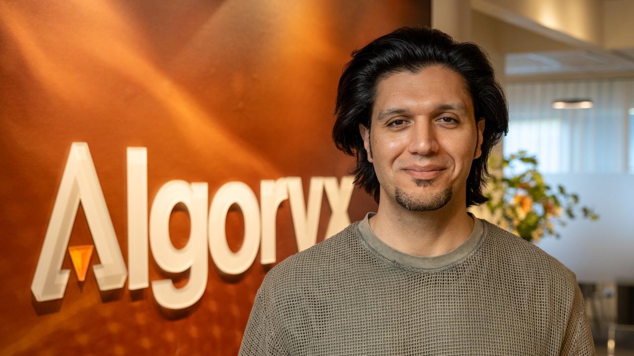 Porträttfoto på Omar Abrahamsson, i bakgrunden Algoryx logotyp mot röd vägg.