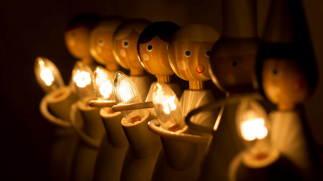 Adventsdekoration i form av trädockor med ljus som bildar luciatåg.