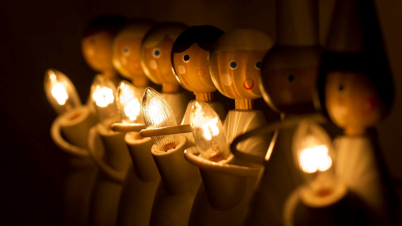 Adventsdekoration i form av trädockor med ljus som bildar luciatåg.