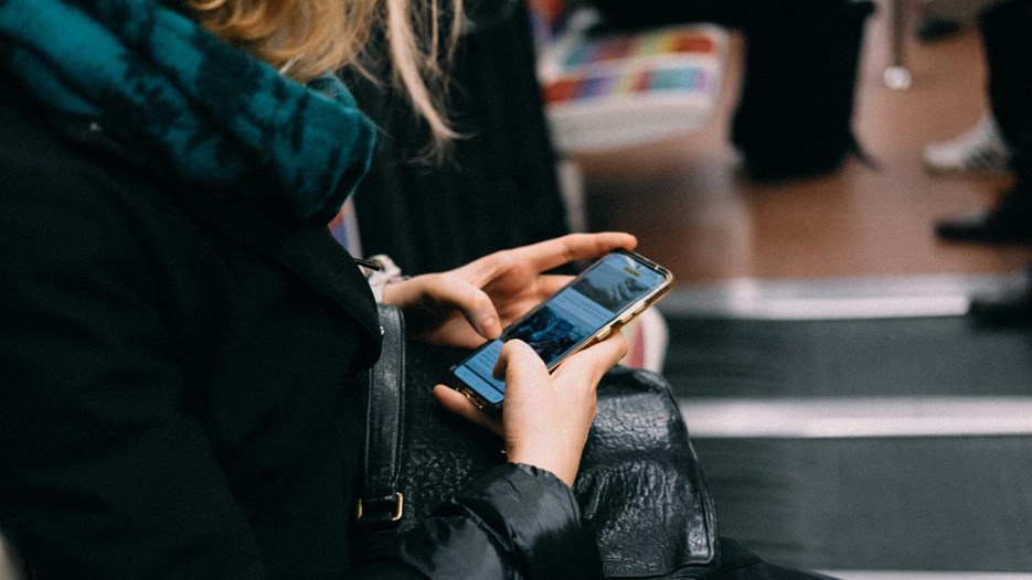 En person som sitter på en bänk och pratar i mobiltelefon.