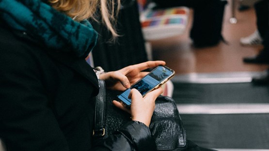 En person som sitter på en bänk och pratar i mobiltelefon.