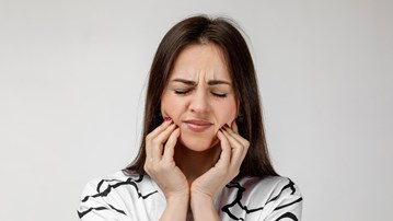 Woman with tooth ache holding her jaw.