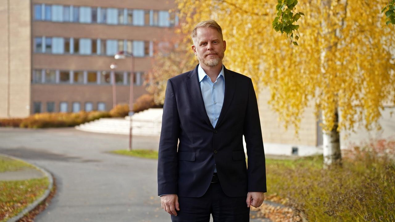 A man in front of a tree with yellow leafs.