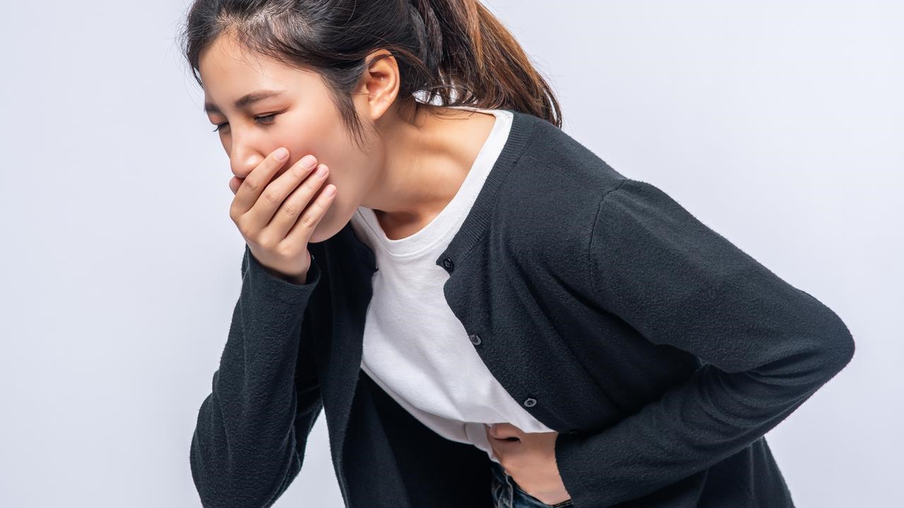 kvinna som tar sig för magen och munnen