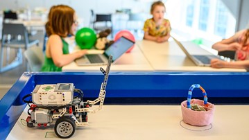 A LEGO robot in Curiosum’s Tech Lab, with three children in the background.