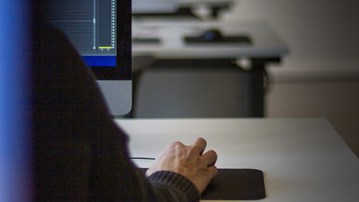 Person vid dator i datasal för digital medieproduktion. 