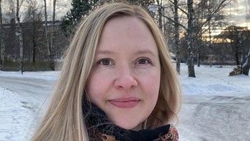 En kvinna med långt blont hår står i snön.