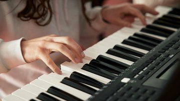 Flicka spelar piano.