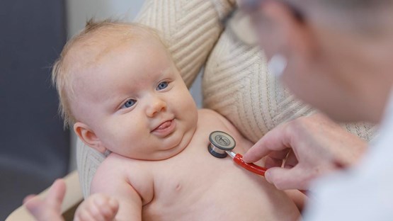 A doctor is checking the heart of a baby with a stetoscope.
