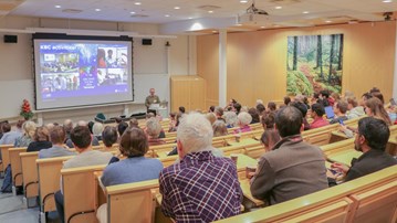 The presenter is talking to the audience in the lecture hall
