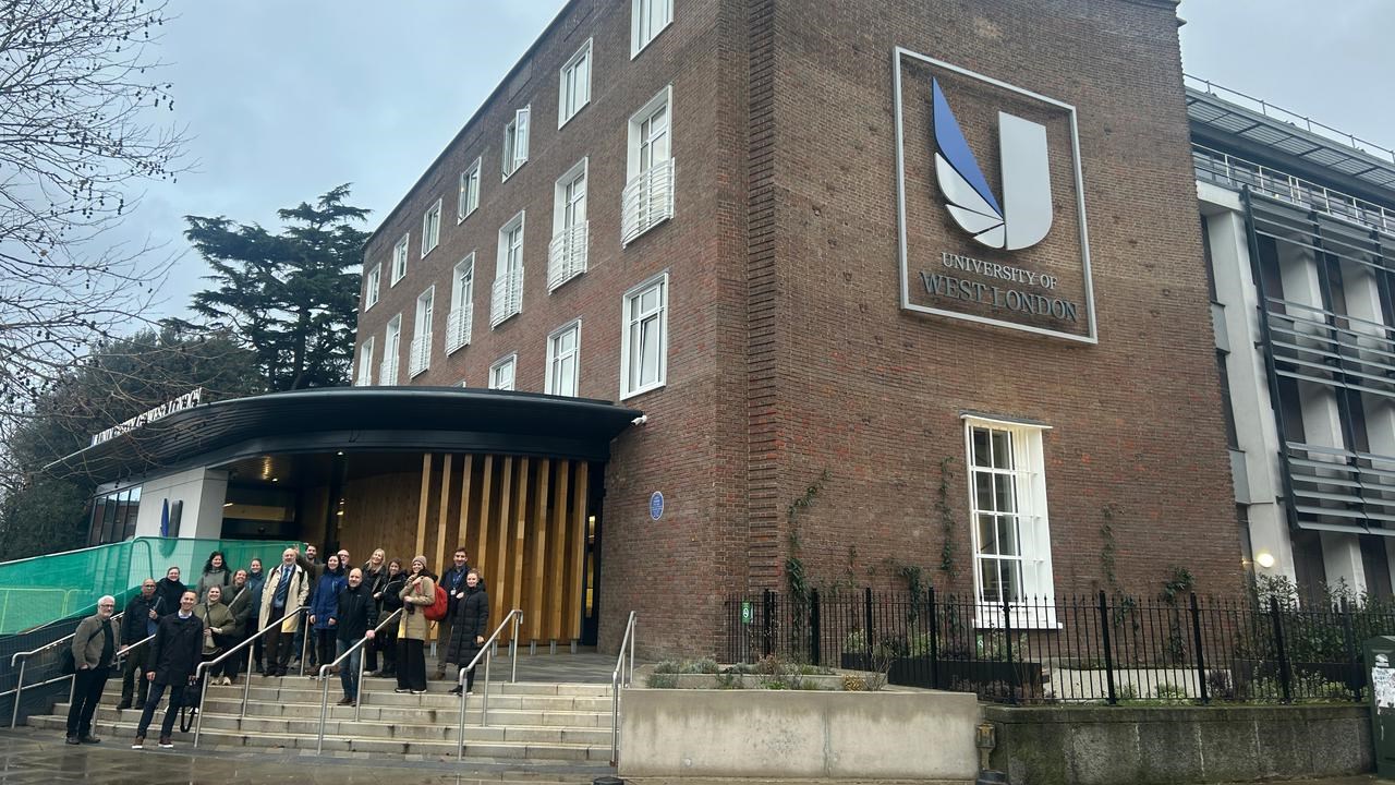 En grupp m&auml;nniskor som st&aring;r framf&ouml;r en byggnad.