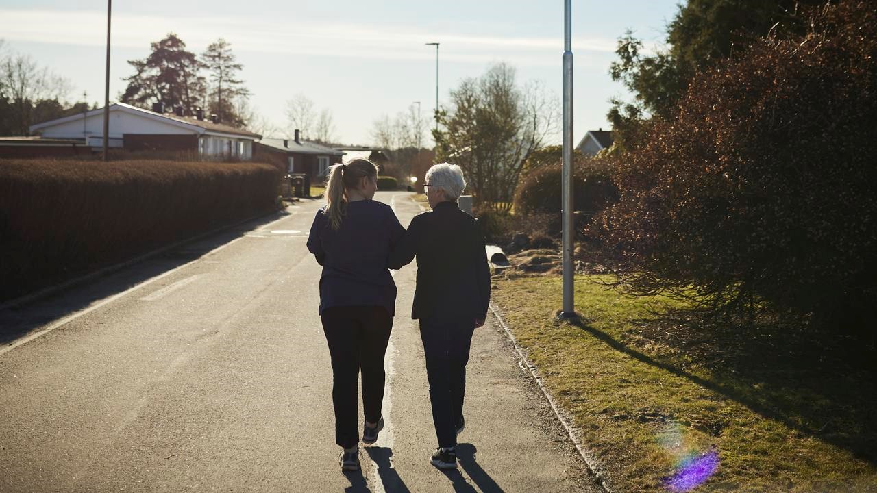 Äldre och yngre kvinna promenerar bort från fotografen
