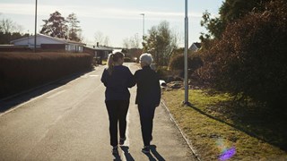 Äldre och yngre kvinna promenerar bort från fotografen