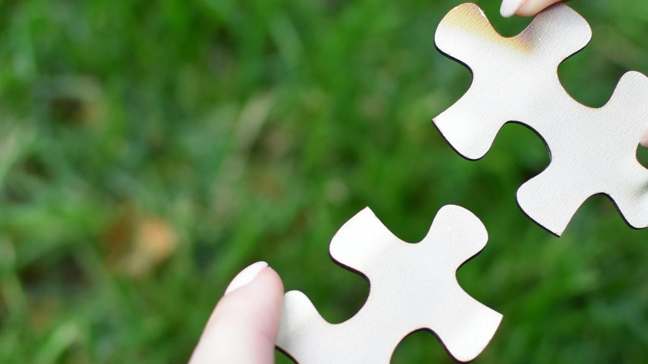 Två händer som håller ihop pusselbitar