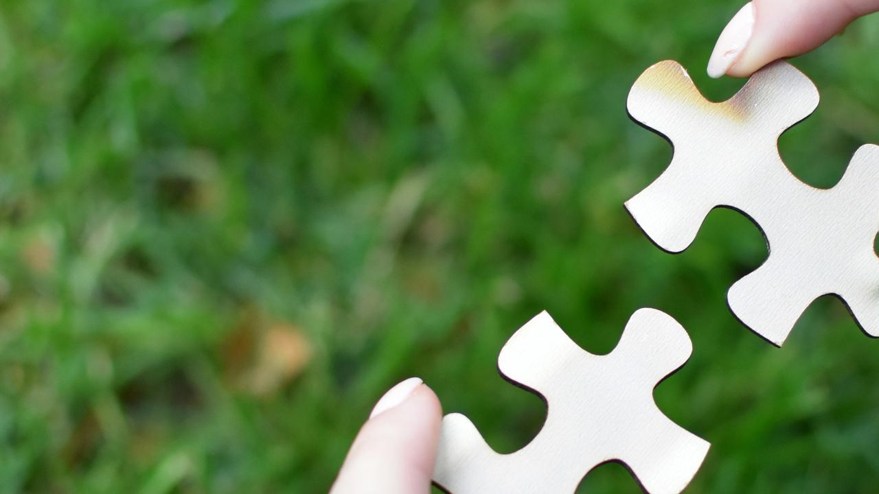 Två händer som håller ihop pusselbitar
