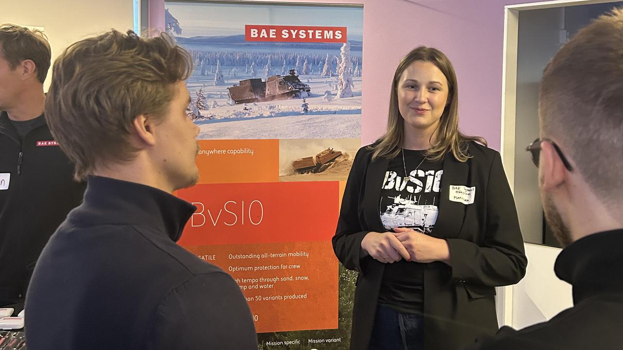 Bild på företagsrepresentant och två studenter kring en monter
