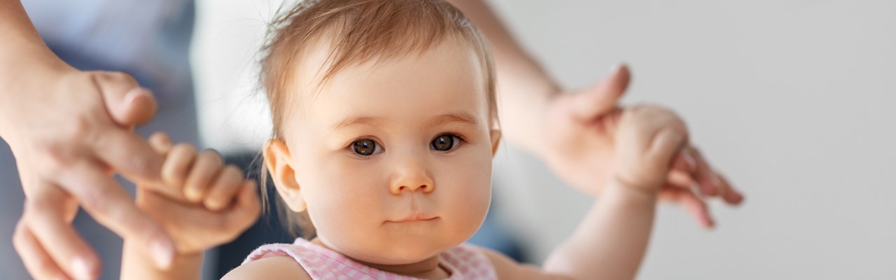 Liten flicka lär sig gå med hjälp av sin mamma.