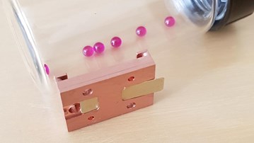 En glasburk fylld med rosa pärlor på ett bord.