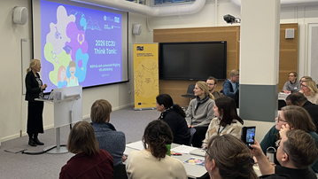 En grupp människor i ett rum med en projektorduk.