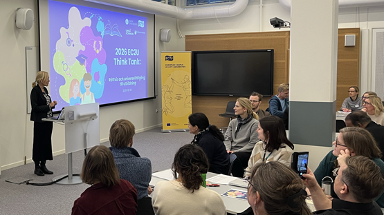 En grupp människor i ett rum med en projektorduk.