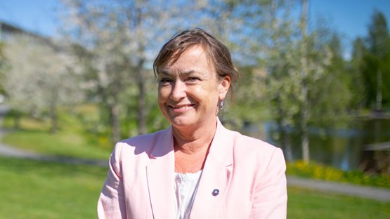 Tora Holmberg i rosa kavaj framför Campusdammen en solig sommardag.