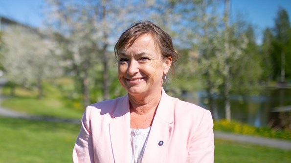 Tora Holmberg i rosa kavaj framför Campusdammen en solig sommardag.