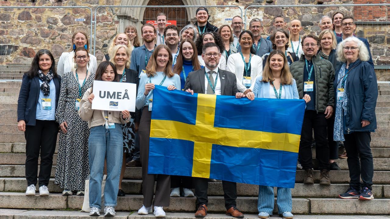 A group of people standing on steps holding a flag.