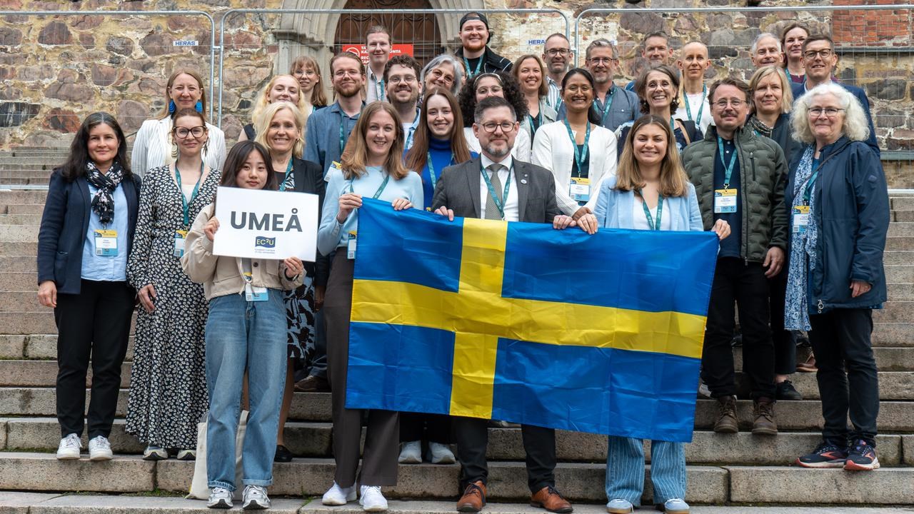 A group of people standing on steps holding a flag.