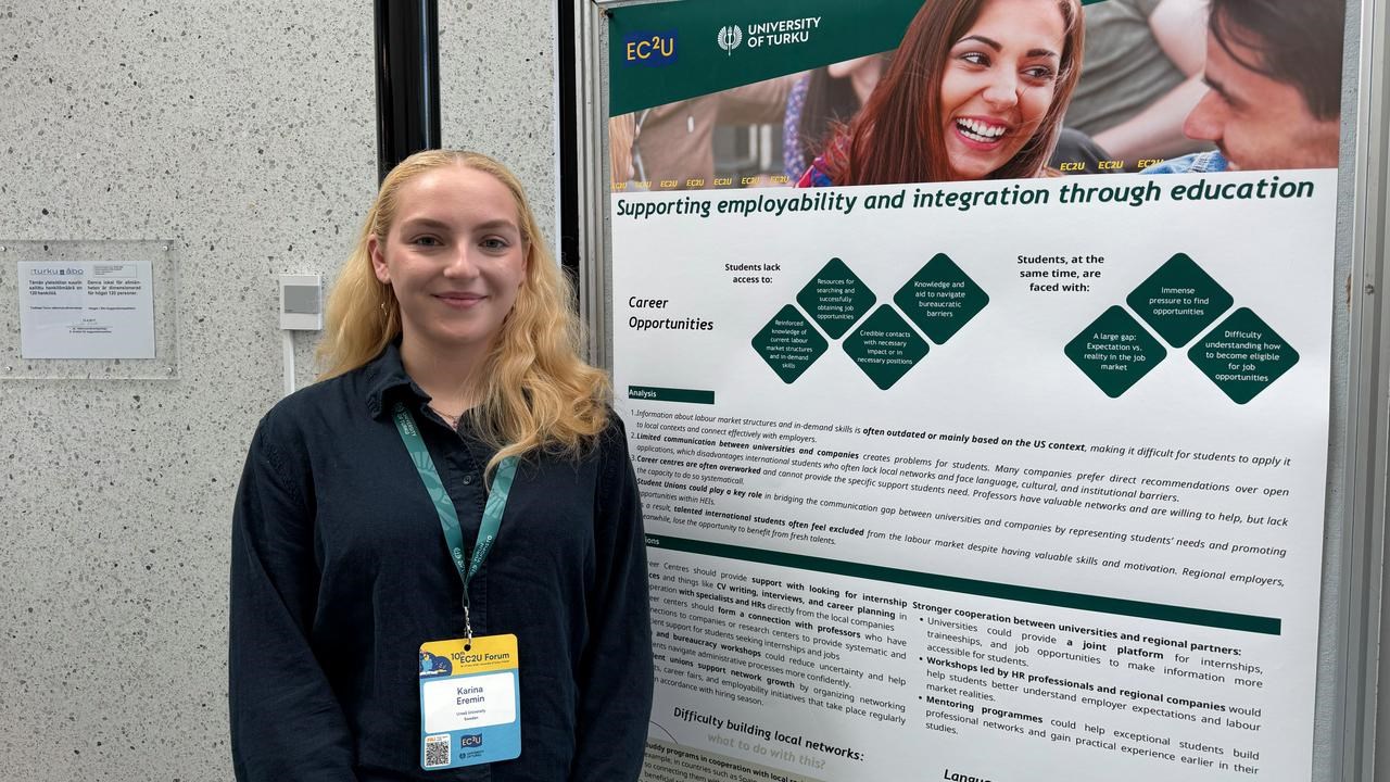 A woman standing in front of a poster.