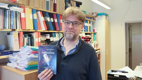 Porträtt på Jörgen Johansson som håller i sin bok