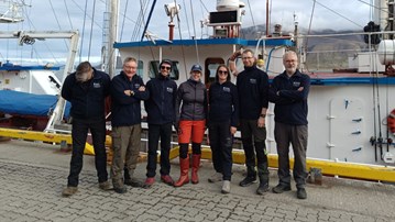 Gruppbild på forskarteam framför en båt på väg till Eidembukta, Svalbard.