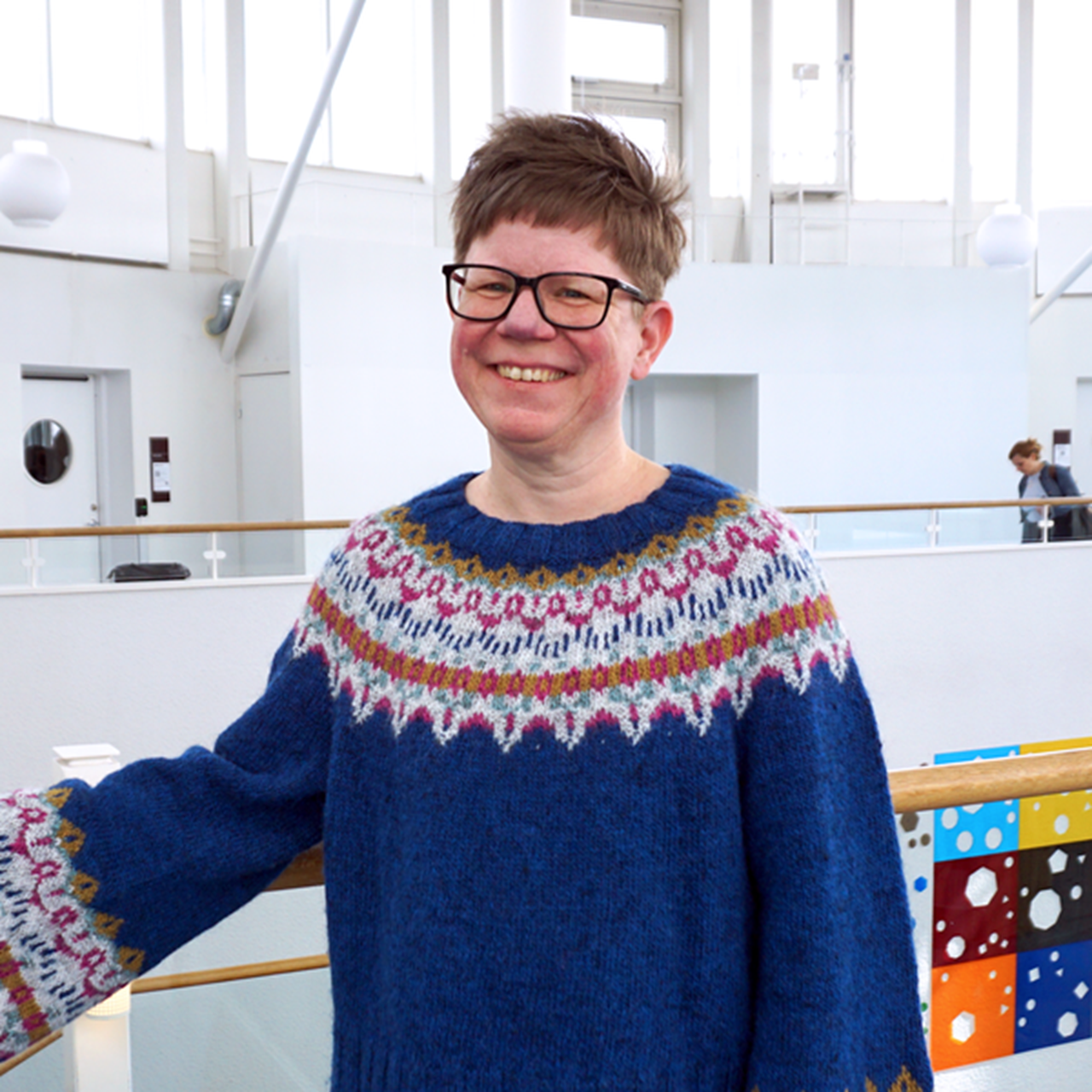 En kvinna i bl&aring; tr&ouml;ja st&aring;r p&aring; ett r&auml;cke.