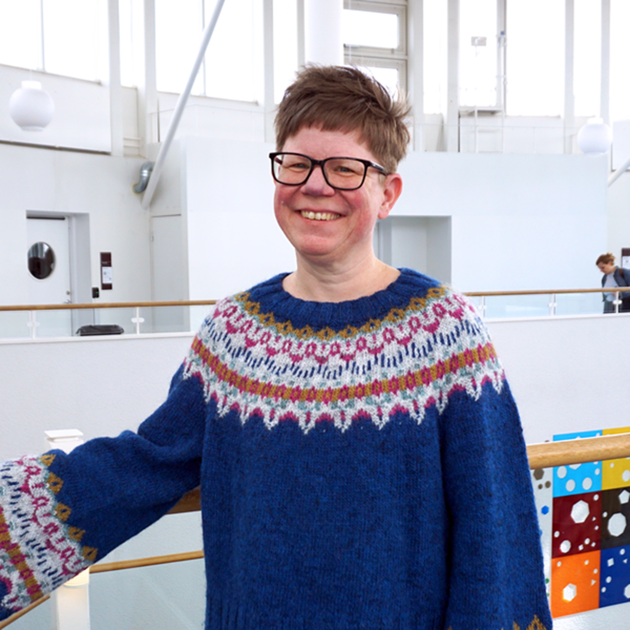 En kvinna i bl&aring; tr&ouml;ja st&aring;r p&aring; ett r&auml;cke.