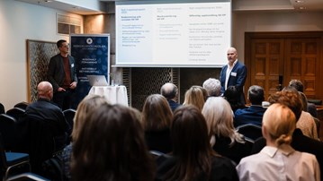 Två män som håller en presentation för en grupp människor.