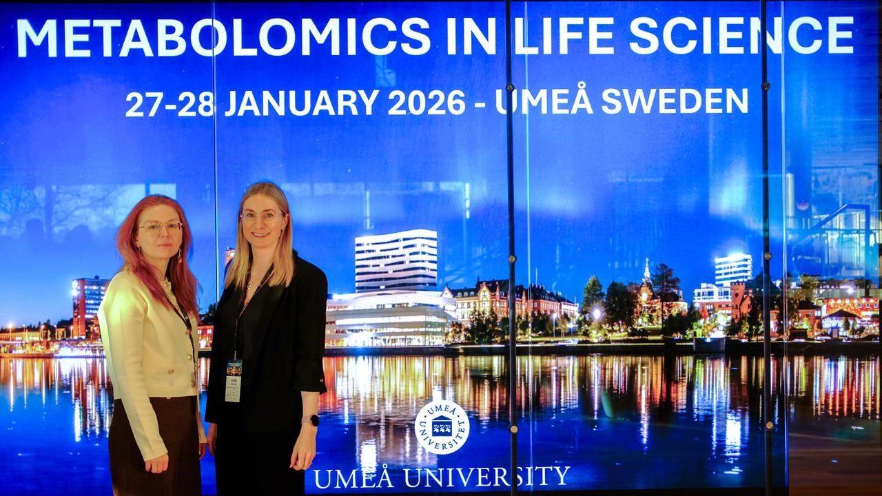 Two women standing next to each other in front of a screen at the scientific conference.