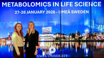 Two women standing next to each other in front of a screen at the scientific conference.