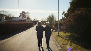 Äldre och yngre kvinna promenerar bort från fotografen