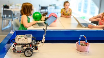 Legorobot i Curiosums tekniklabb. I bakgrunden syns tre barn.