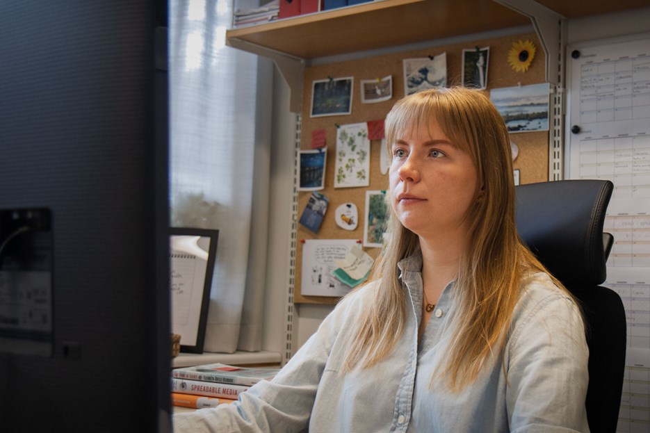 En kvinna sitter framför en datorskärm på ett kontor. 