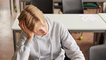 Bild på skoltrött pojke sittande i klassrum