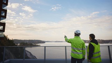 Två byggnadsarbetare pekar mot byggnad