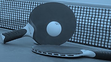 Two ping pong paddles and a racket on a tennis court.