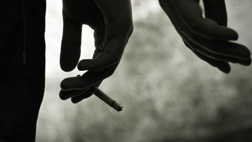 Närbild på hand som håller cigarett.