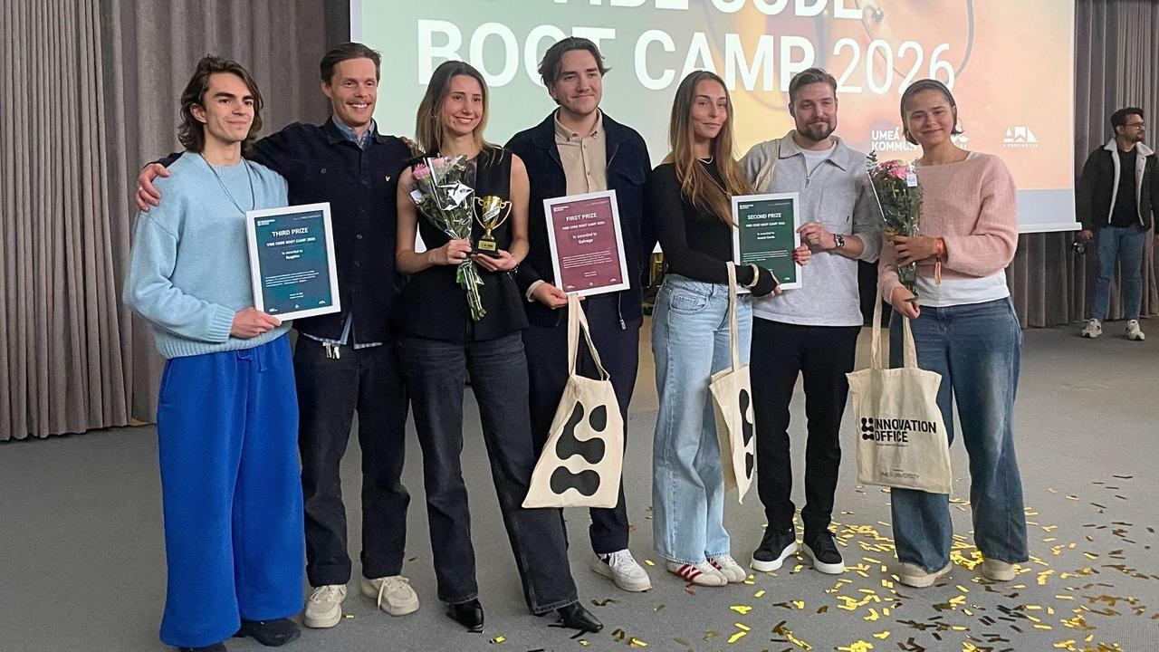 Bilden f&ouml;rest&auml;ller sju personer som h&aring;ller i blommor, tygkassar och diplom. I bakgrunden syns texten welcome back to Vibe code Boot Camp 2026 p&aring; sk&auml;rm.